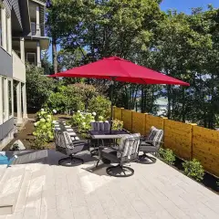 Large-format paver terrace with outdoor dining furniture beside a multi-unit building and cedar fence
