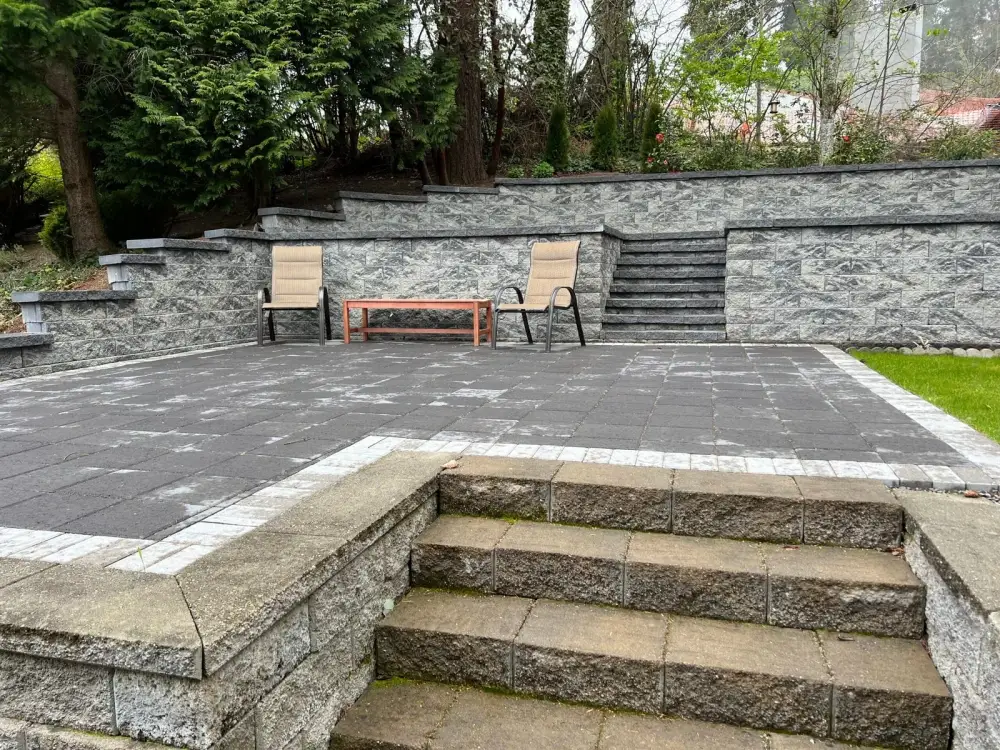 Terraced grey stone patio with wide steps and a seating area on a steep back garden
