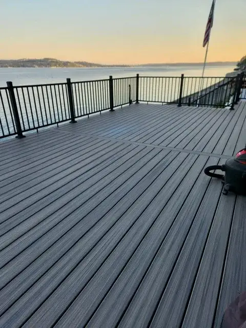 Wide composite deck with a slim black metal picket railing looking out over open water at sunset from a Capitol Hill property