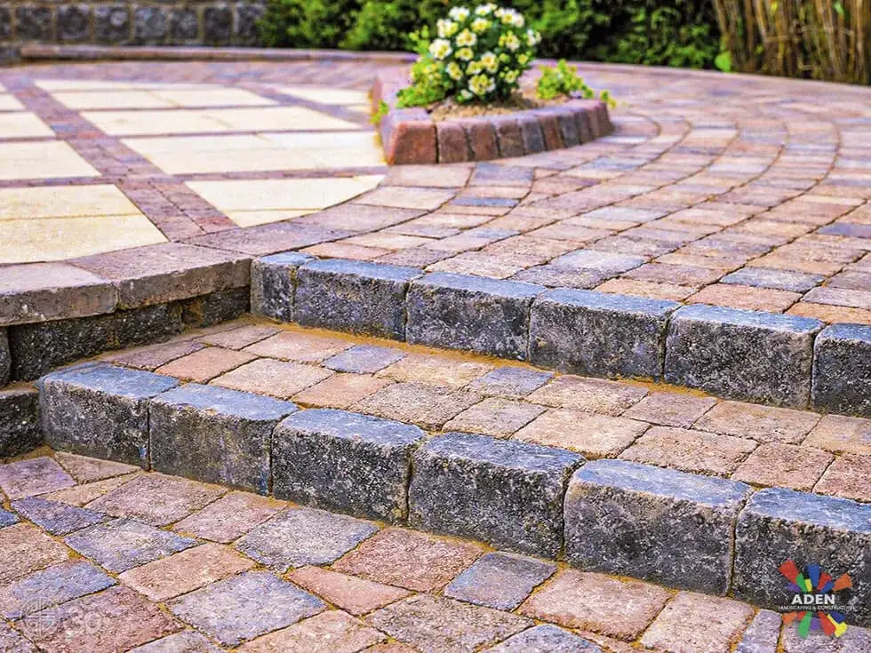 Detail of tumbled paver steps with a contrasting soldier-course border meeting a large-format patio field