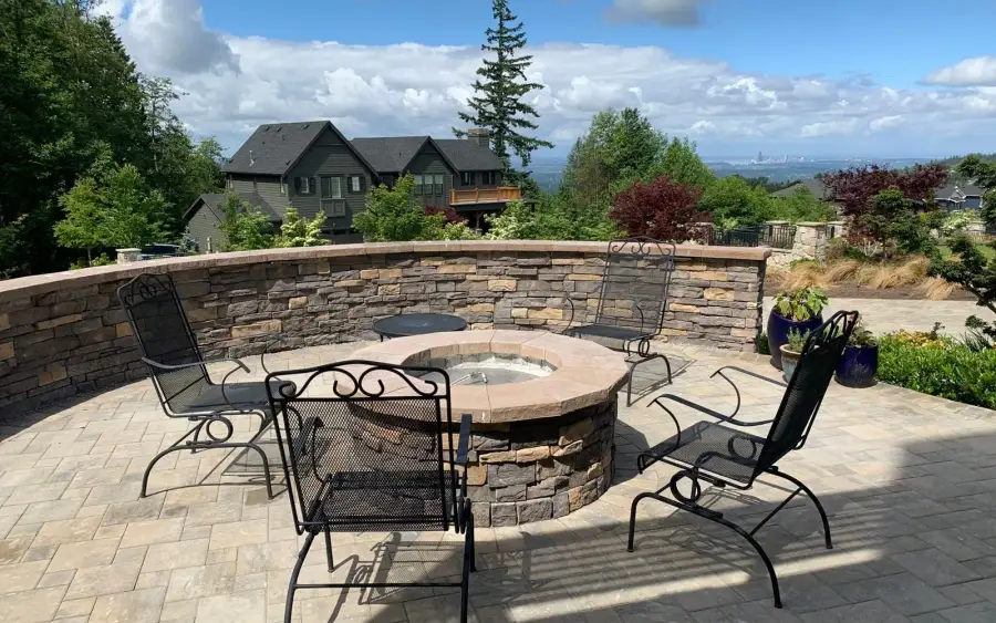 Circular stone fire pit and curved seat wall on a paver patio overlooking a valley view