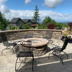 Circular stone fire pit and curved seat wall on a paver patio overlooking a valley view