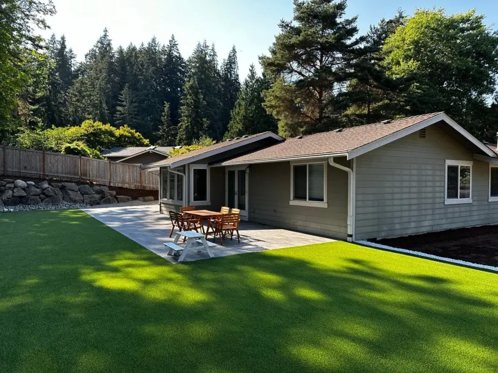 Artificial turf lawn and paved patio running the full width of a single-storey house