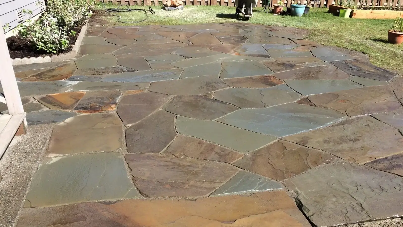 Hand-fitted natural flagstone patio in a fenced back garden