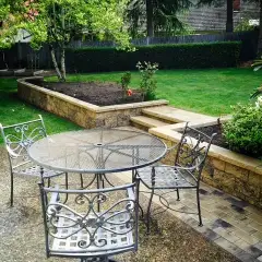 Capped stone seat wall edging a paved terrace with planting behind it