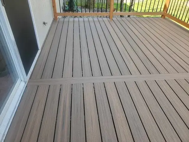Composite deck in grey and brown tones with a contrasting border board, laid up to a sliding patio door on a Newcastle house