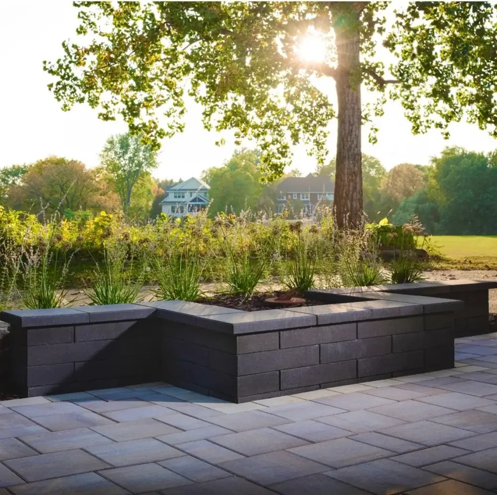 Charcoal block raised planters framing a stone terrace in evening light
