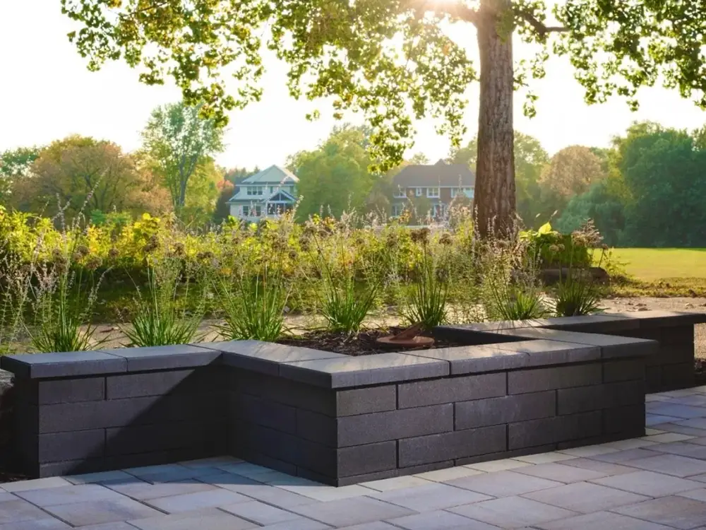 Charcoal block raised planters framing a stone terrace in evening light