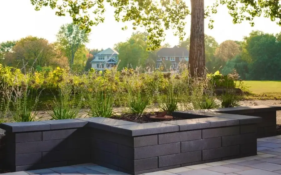 Charcoal block raised planters framing a stone terrace in evening light on a Newcastle property