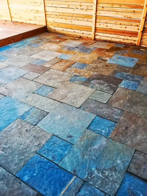 Slate patio in blue, rust and grey tones laid in a random pattern, enclosed by a new horizontal cedar screen fence
