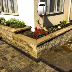 Stone-faced raised planting beds filled with fresh soil beside a paved path