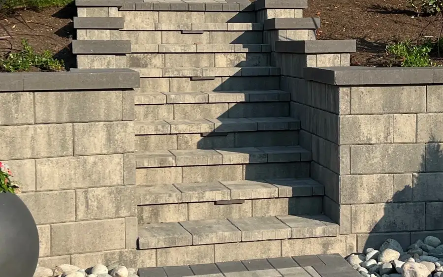 Block retaining wall with steps built into the wall face and a rock drainage edge on a Queen Anne slope