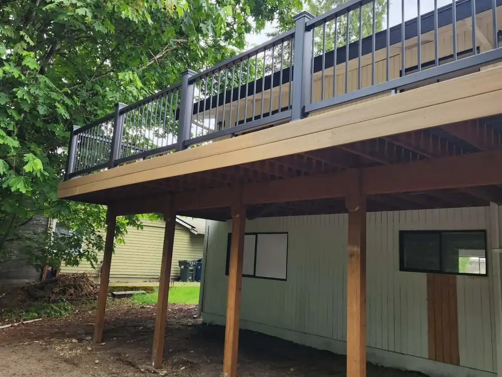 Elevated composite deck on cedar posts with black aluminium railing spanning the back of a Redmond house above a daylight basement