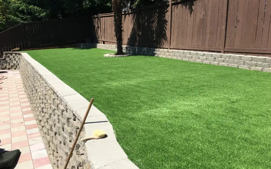 Artificial turf lawn held level by split-face block retaining walls with a paver walk alongside in Redmond