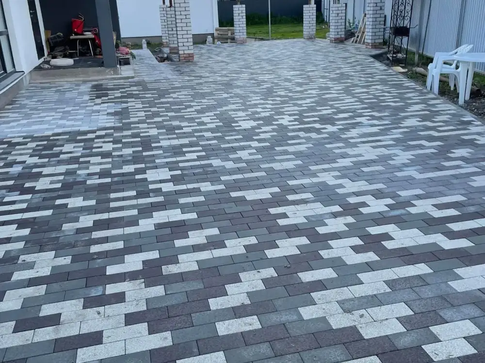 Large modern patio of long grey and white plank pavers laid in a running bond beside a covered walkway