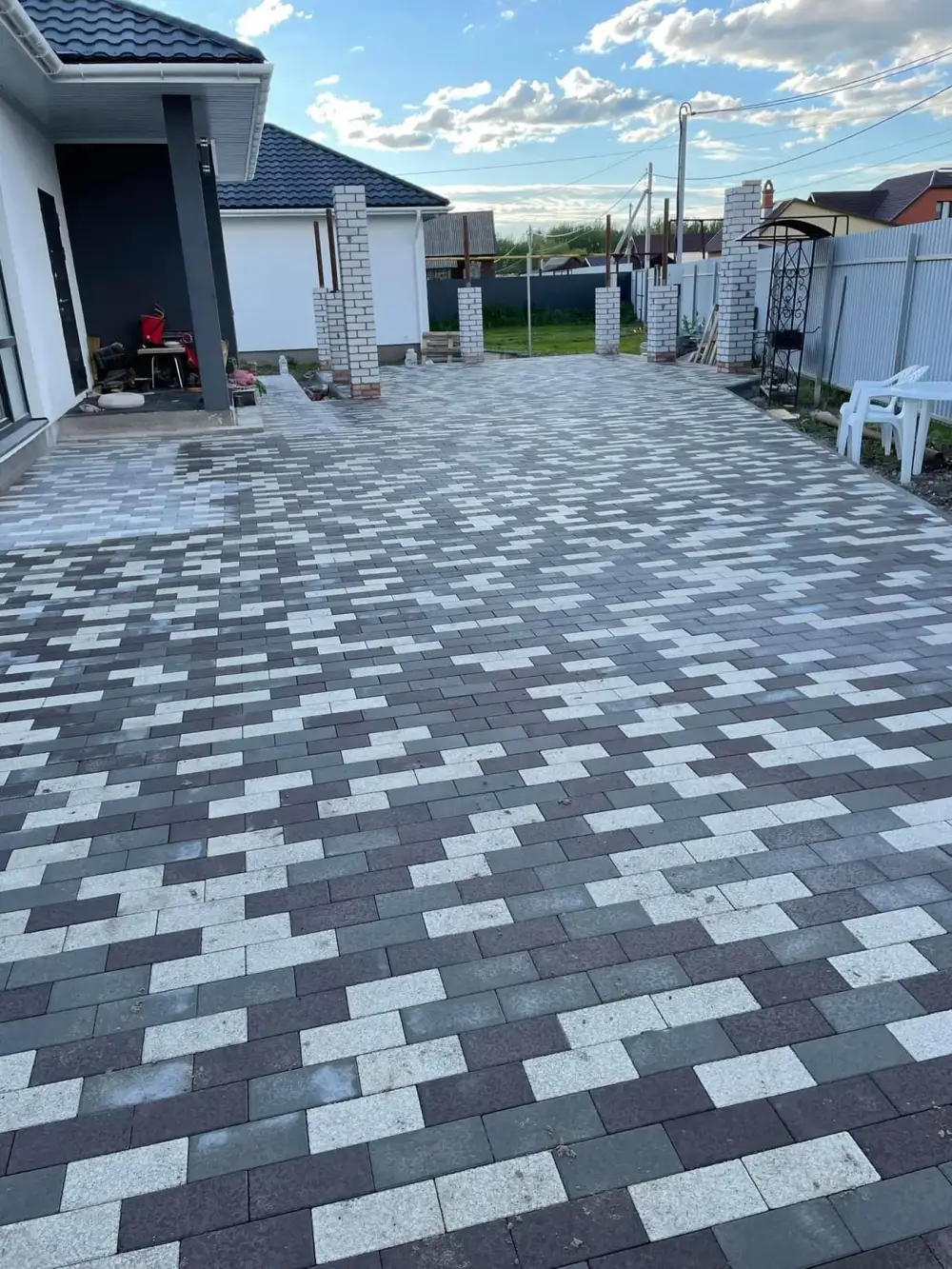 Large modern patio of long grey and white plank pavers laid in a running bond beside a covered walkway