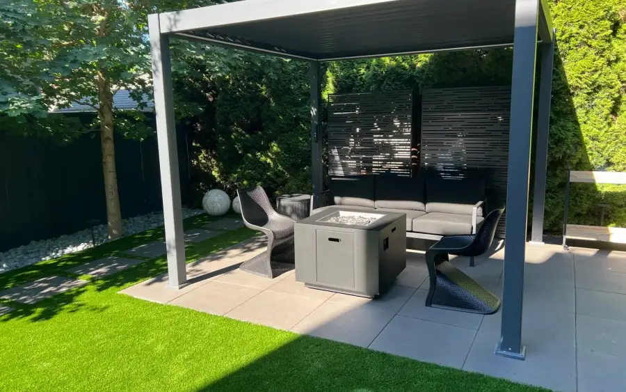 Covered outdoor lounge with a fire table beside an artificial turf lawn on a Seattle property