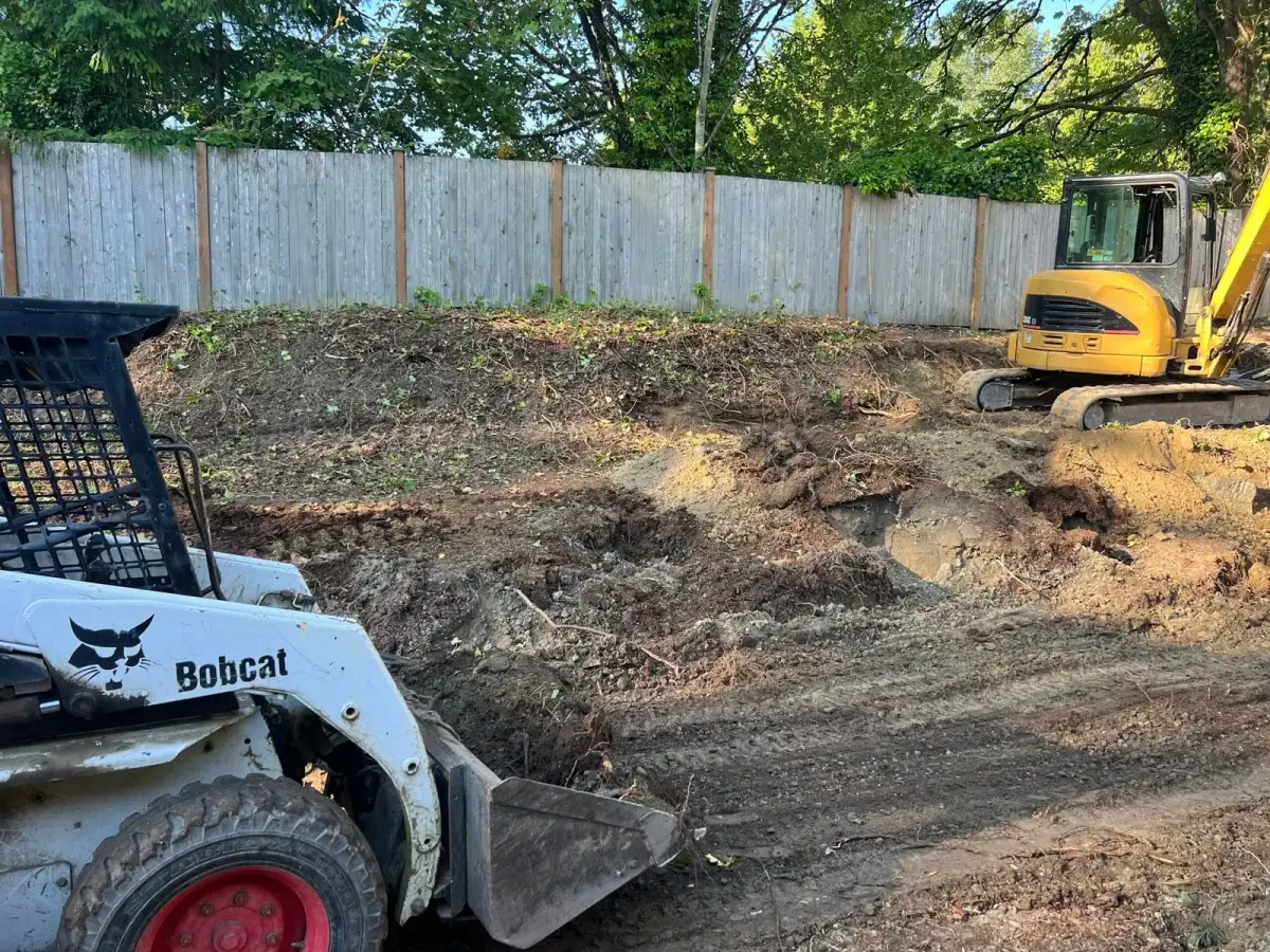 Excavator regrading a yard for drainage before landscape construction