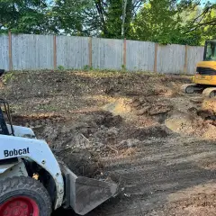 Excavator regrading a yard for drainage before landscape construction