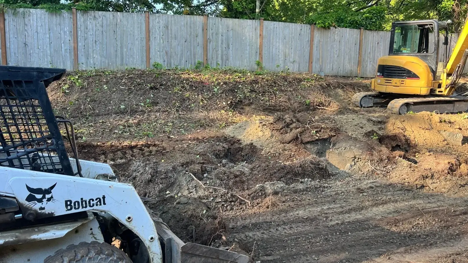 Excavator regrading a Seattle yard for drainage before landscape construction