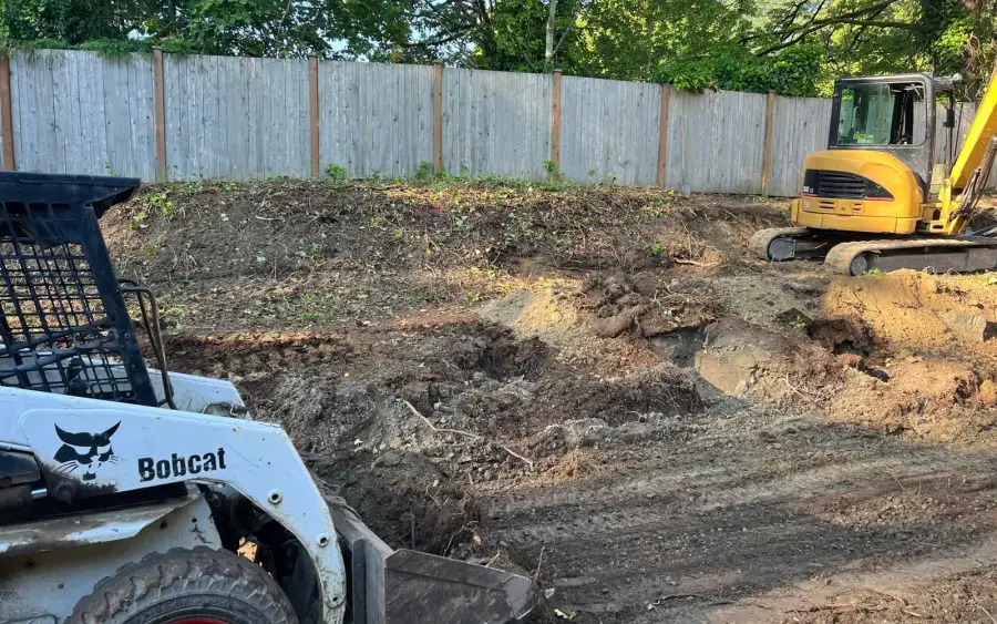 Excavator regrading a yard for drainage before landscape construction