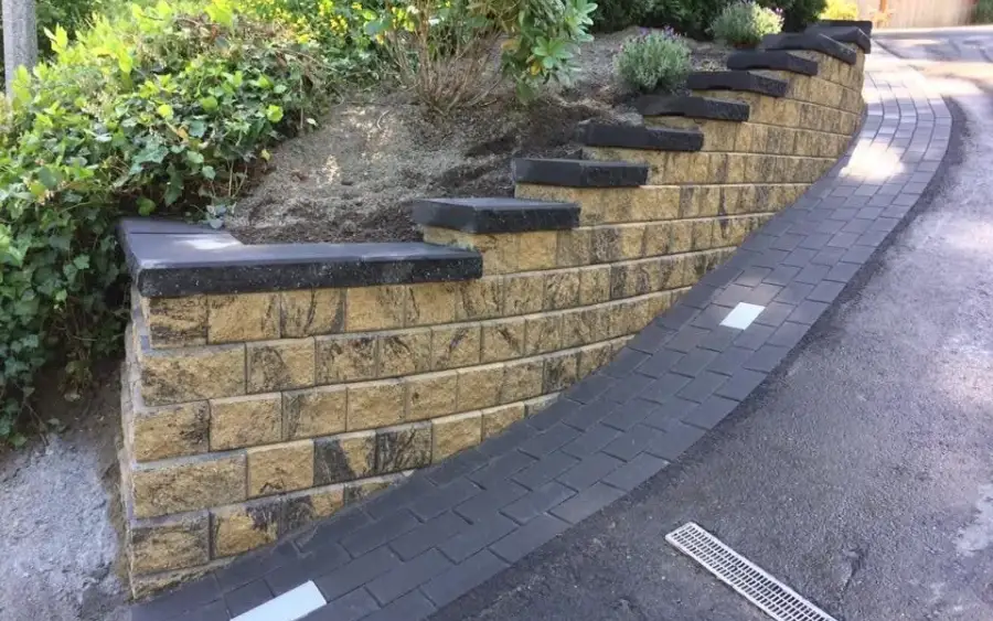 Curved street-frontage retaining wall with recessed lighting and planting above it in south Seattle