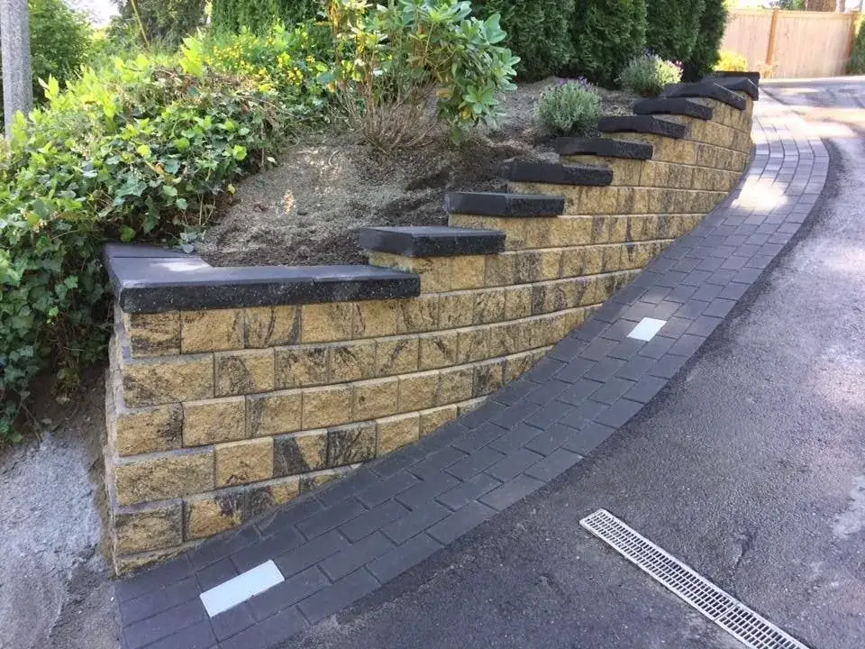 Curved street-frontage retaining wall with recessed lighting and planting above it