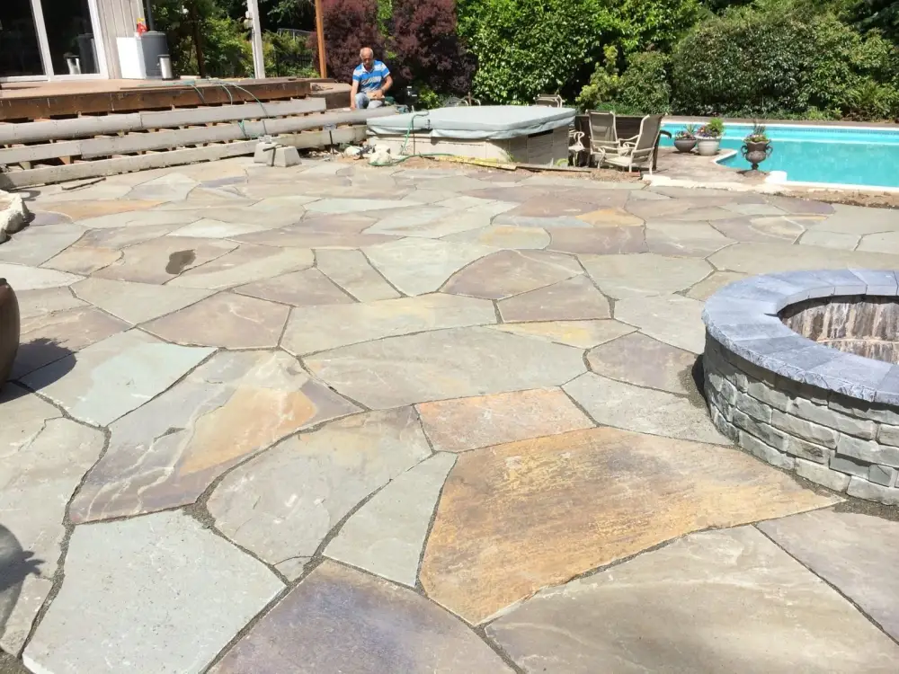 Irregular flagstone terrace fitted around a hot tub and a circular fire pit