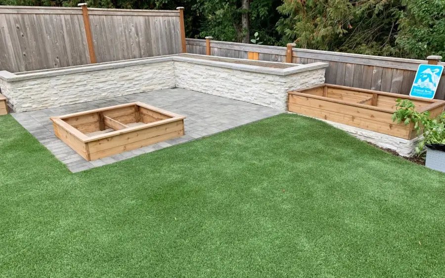 Artificial turf lawn framed by cedar raised planter beds and a paved seating area in West Seattle