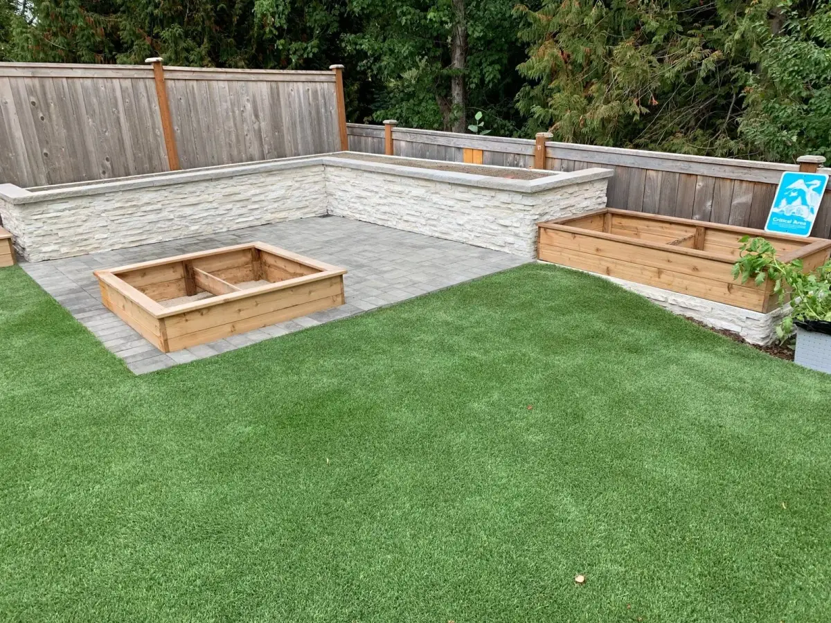 Artificial turf lawn framed by cedar raised planter beds and a paved seating area
