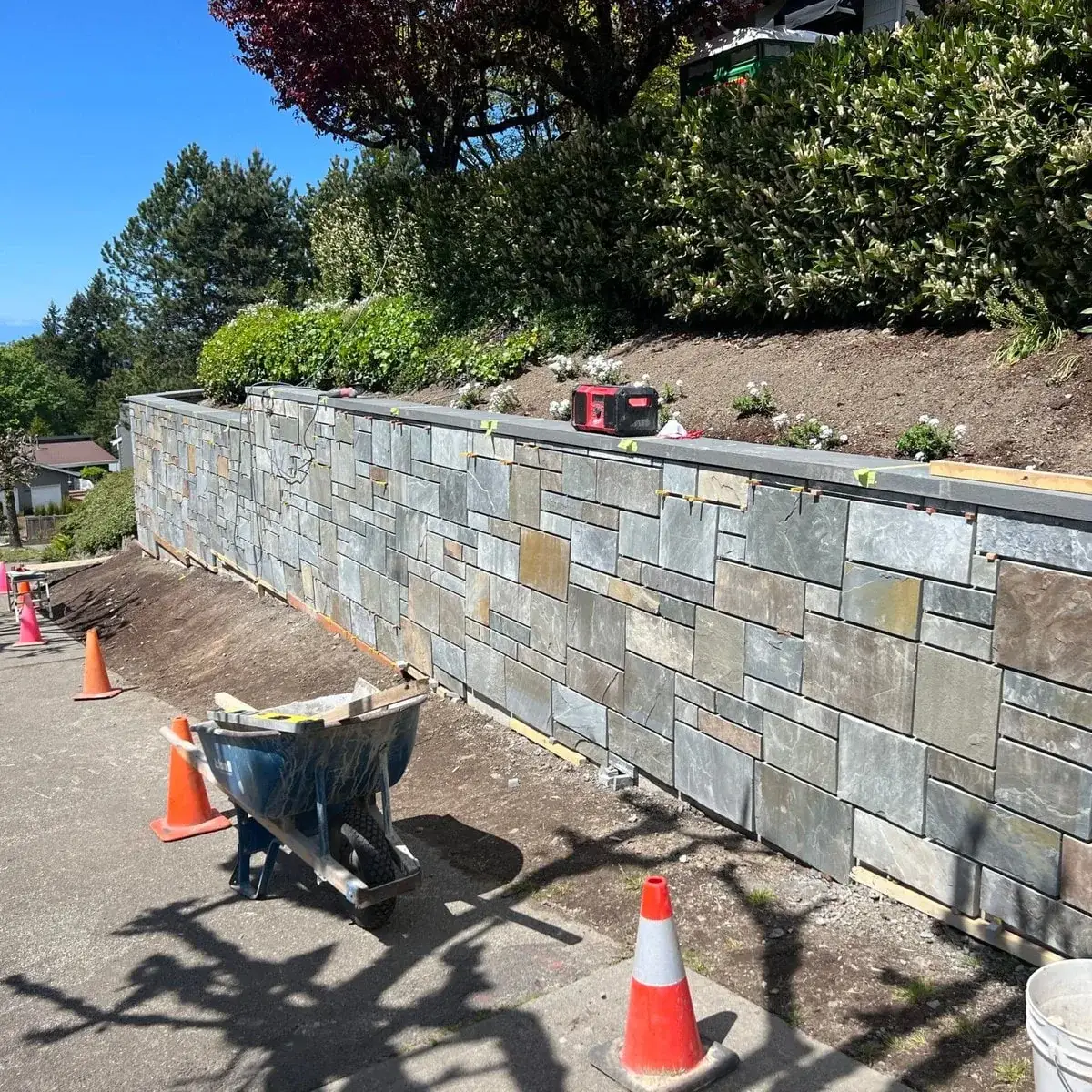Natural stone veneer retaining wall part-built on an Aden Landscaping job site